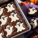 Fudgy Halloween ghost cheesecake brownies topped with white cheesecake ghosts and chocolate eyes